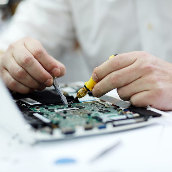 Closeup shot of male hands  working on disassembled laptop with screwdriver and tweezers looking for broken pats